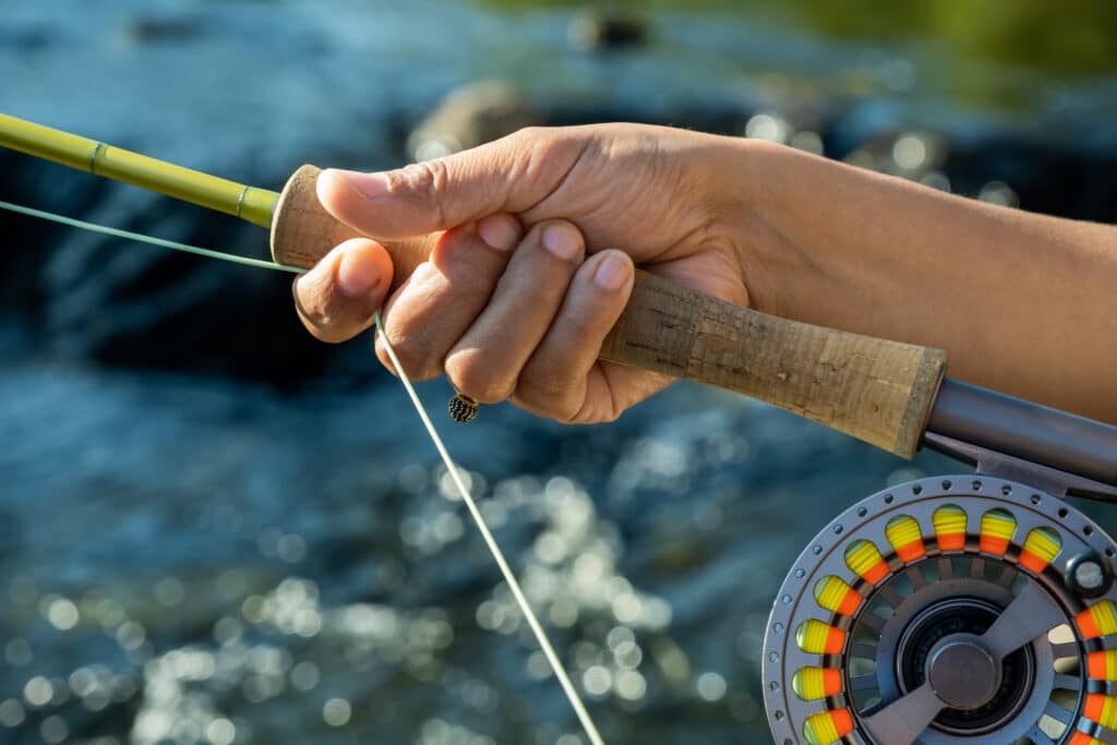 Close up of a young female asian hand stripping fly fishing line on a river